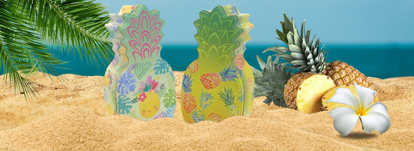 Banner beach scene with pineapples, plumeria, palm leaves, and pineapple shaped tins.