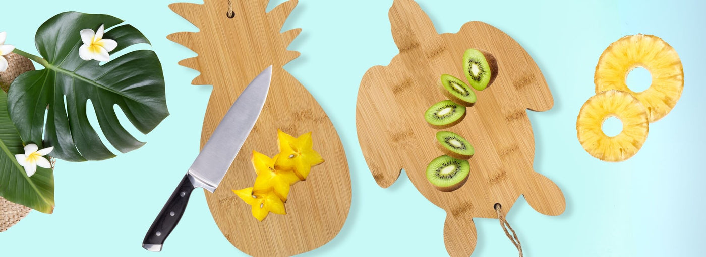 Light blue banner with tropical plants, flowers, and fruit. A knife and Hawaii pineapple and turtle shaped cutting boards.