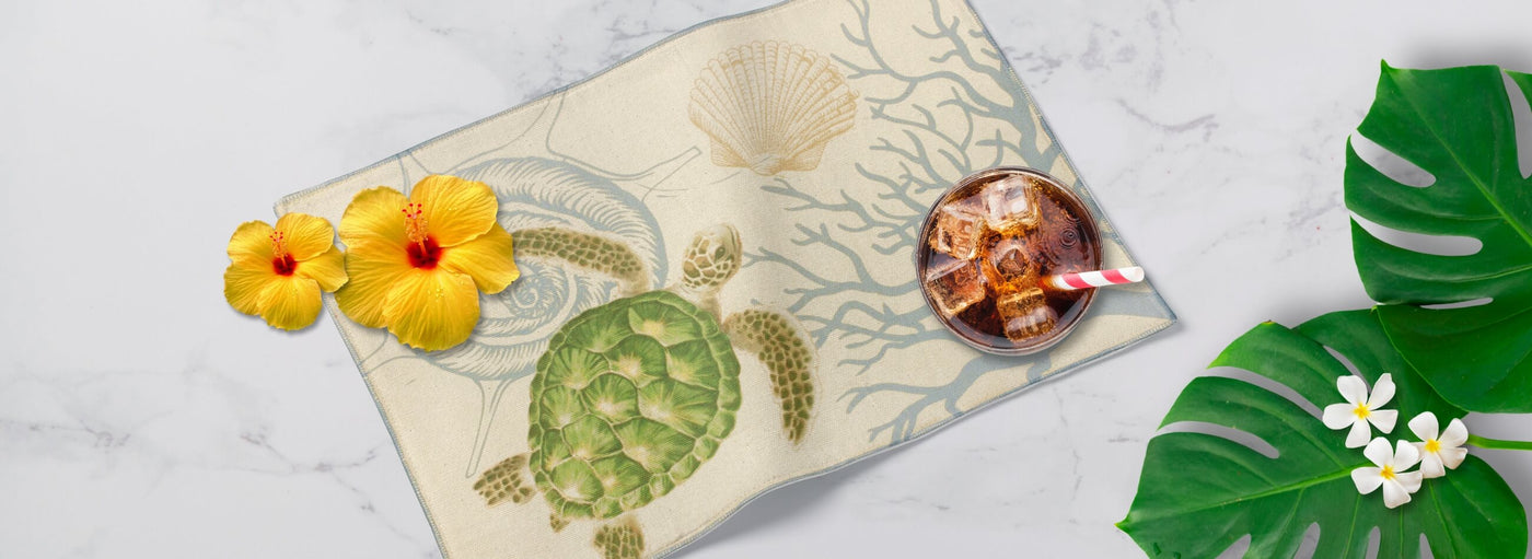 Banner with tropical leaves and flowers, a Hawaiian mat with a sea turtle, and a soda with a staw.