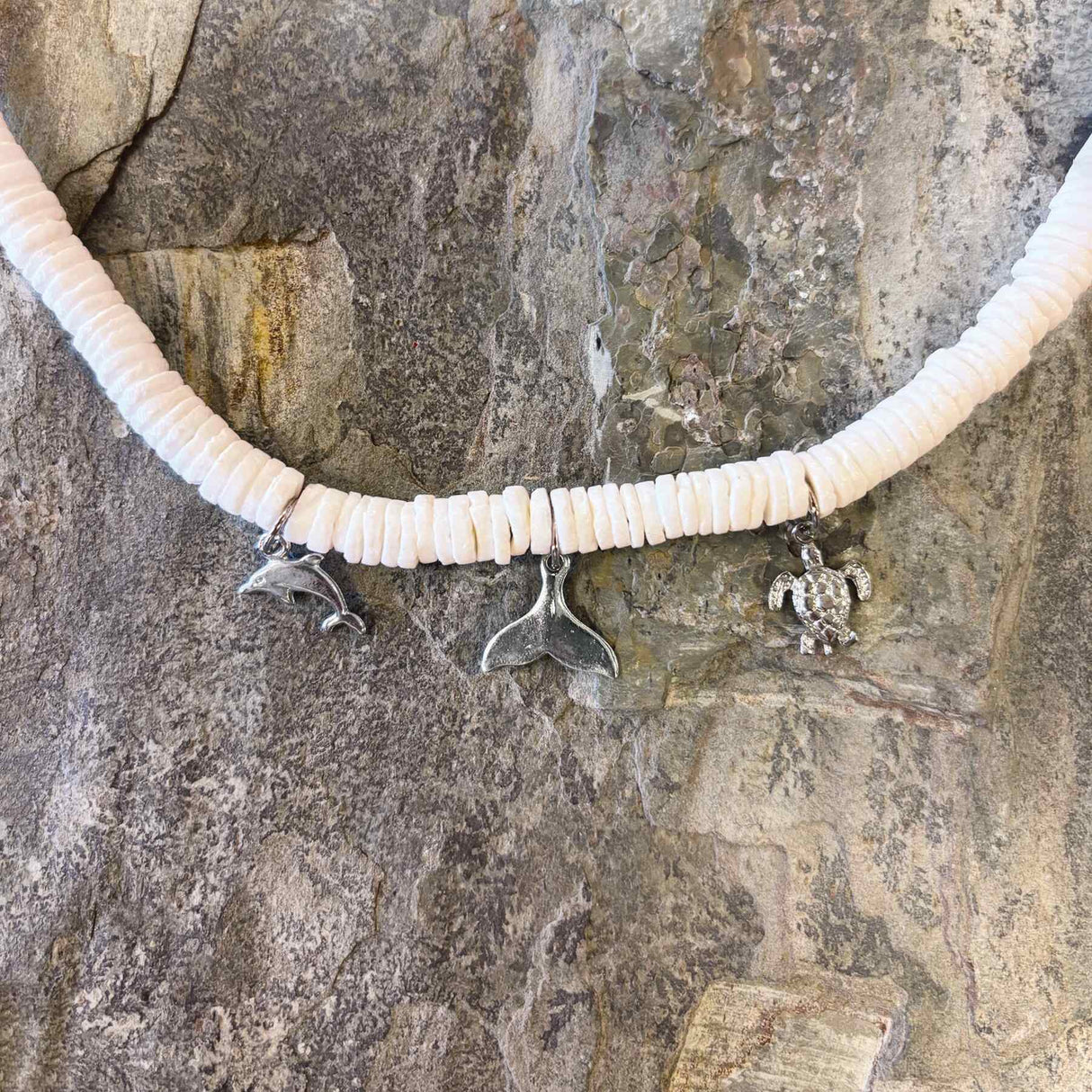 Hawaiian necklace featuring a trio of charms with white clam shell beads