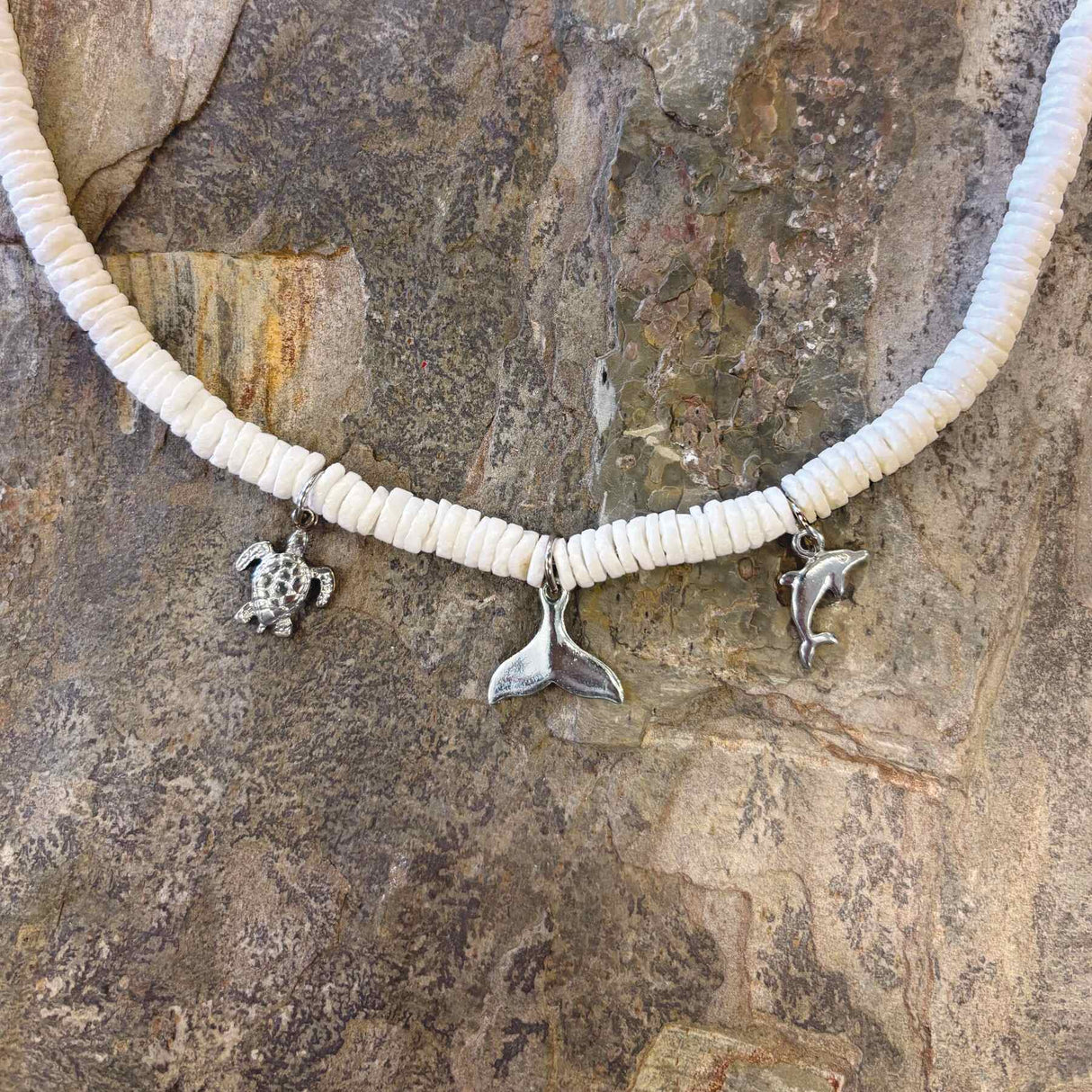 Beachy white clam shell necklace with three dangling charms symbolizing island life
