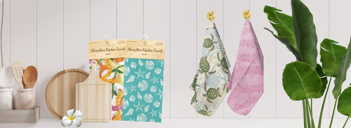 Banner with tropical plants and flowers, Hawaii kitchen towels hanging and in package, wooden trays and cutting board.