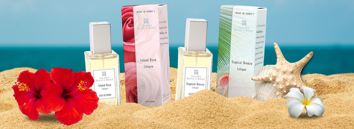 Two packages and two bottles of perfume in sand with blue background and flowers and shells.