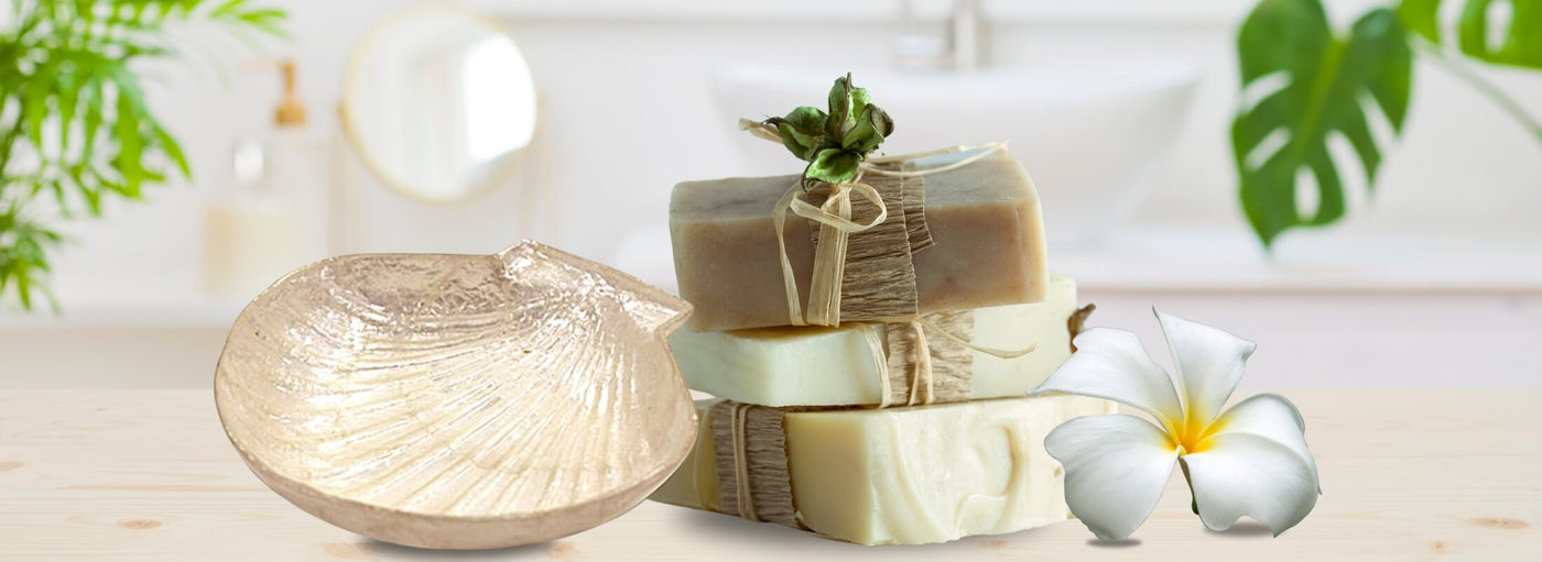 white banner with three soaps wrappd, a plumeria and a clam shell