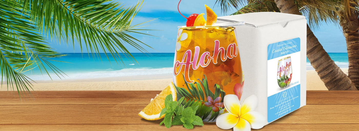 Banner with tropical plants and flowers, beach, box, slice of orange, Hawaii aloha glass cup filled with yellow drink and a cherry on top.