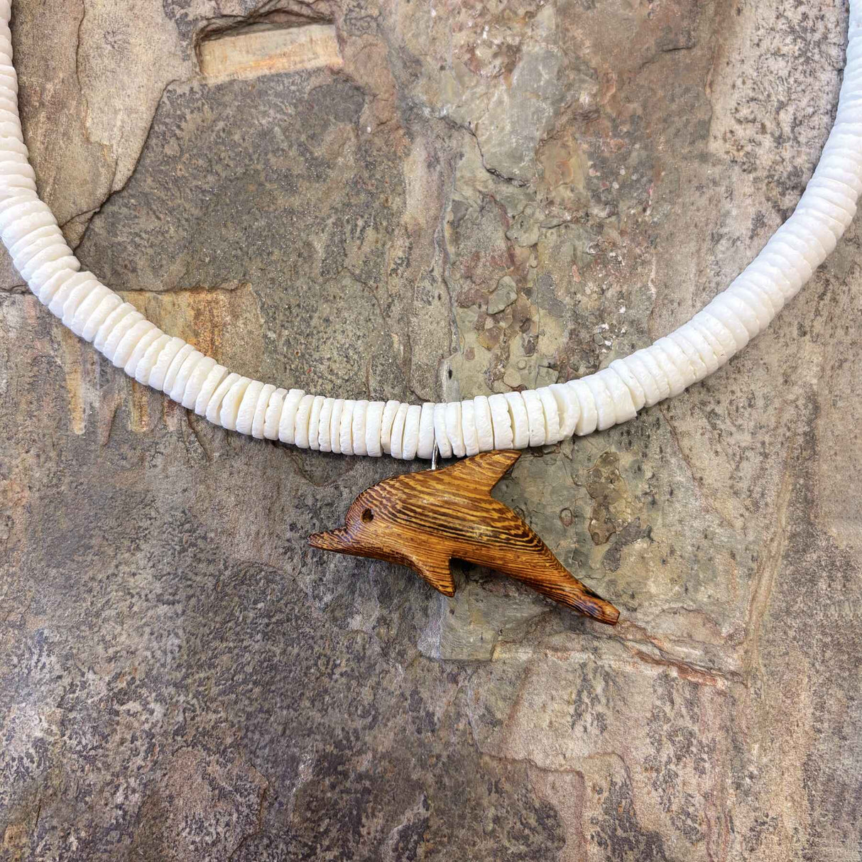 White clam shell necklace featuring a carved wooden dolphin pendant with island-inspired design