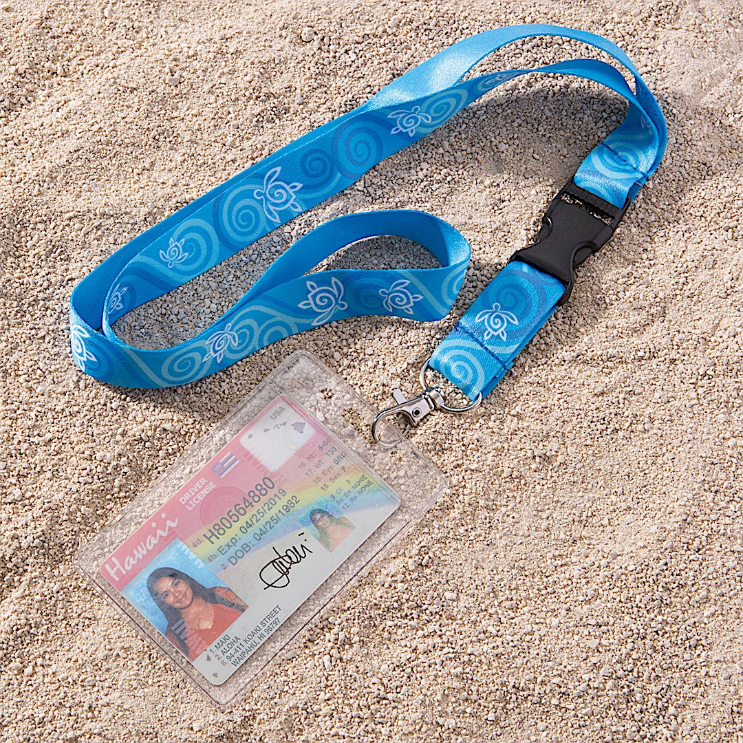 A blue turtle honu lanyard with Hawaii ID attached, laying in the sand