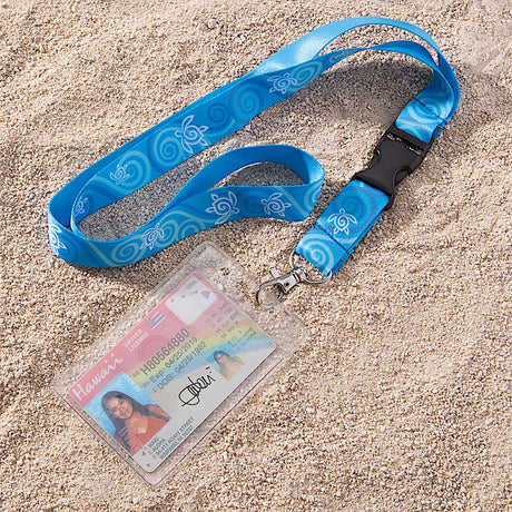 A blue turtle honu lanyard with Hawaii ID attached, laying in the sand