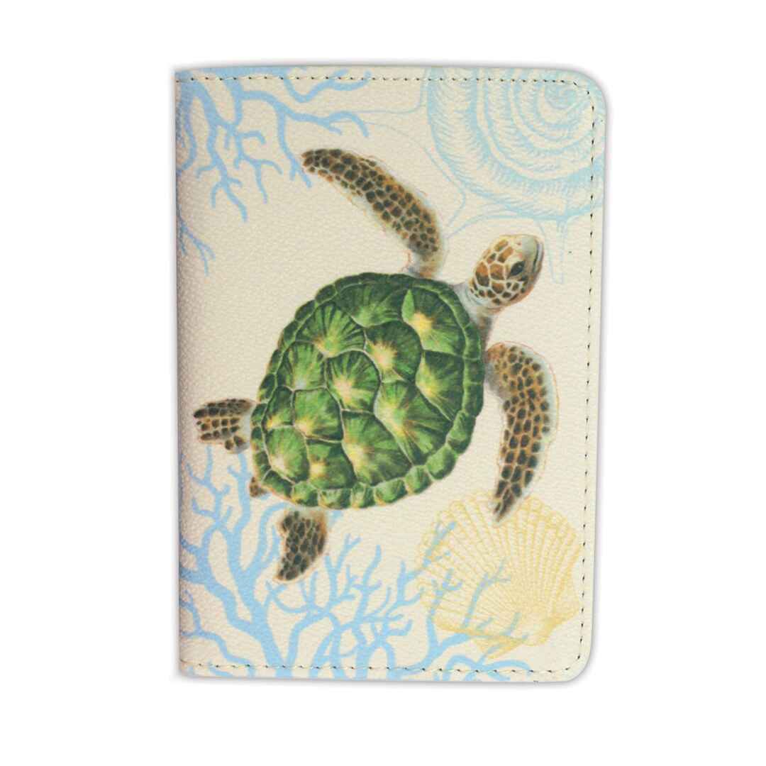 A passport holder with a turtle (honu) design on a beige background, featuring a side pocket and two card compartments.