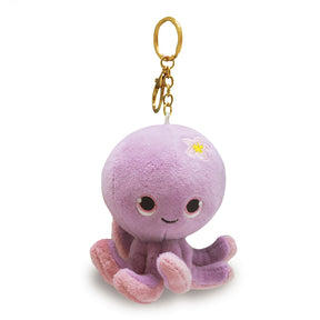 Plush octopus keychain with a gold ring on a light yellow background
