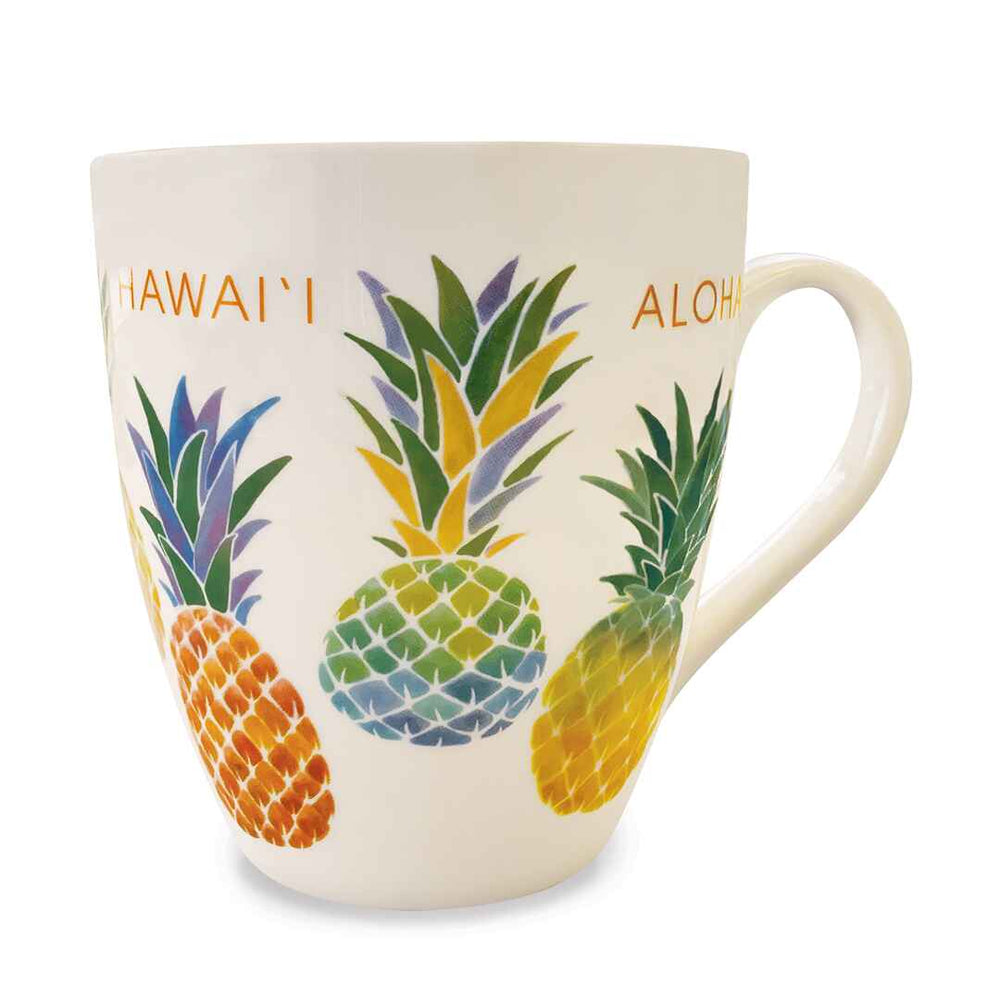 A beige ceramic mug with a colorful illustration of pineapples and the words 'HAWAII' and 'ALOHA' on it.