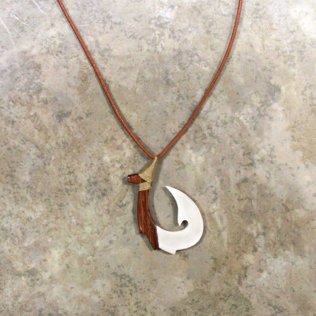 Adjustable necklace featuring a carved brown wood and bone hook design, highlighting detailed craftsmanship and a natural, earthy style.