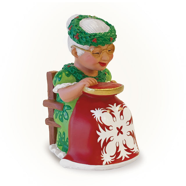 Decorative figurine of an elderly woman in a green outfit with a red and white patterned chair on a white background