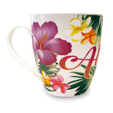 Side view of a white Hawaii mug with the word aloha and some flowers and tropical leaves.