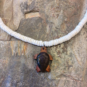 Island-style necklace with a carved wooden turtle pendant and white clam shell accents