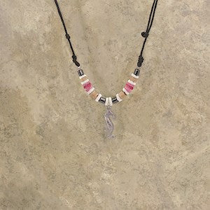 An adjustable necklace with a pewter seahorse pendant, surrounded by beads made of wood, bone, and shell, with an black cord.