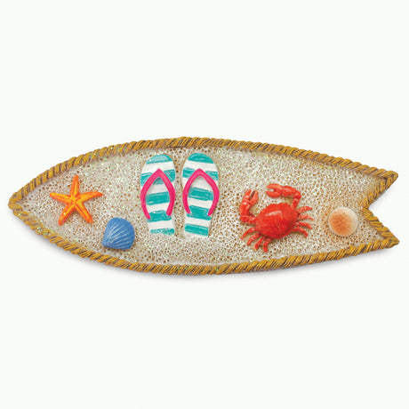 A surfboard-shaped magnet featuring a rope border, textured sand-like center, and small beach-themed accents including a starfish, flip-flops, crab, and shells on a white background.